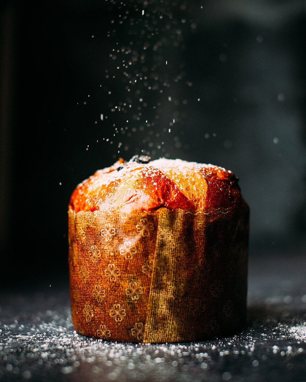 Brioche saupoudrée de sucre glace sur fond sombre.